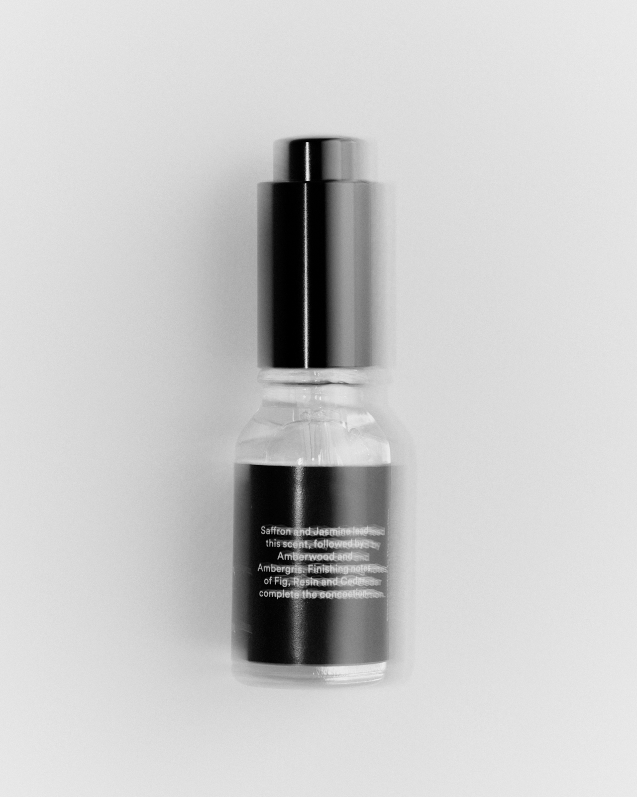 Baccarat aroma oil bottle leaning against matte black tin — product still life Melbourne
