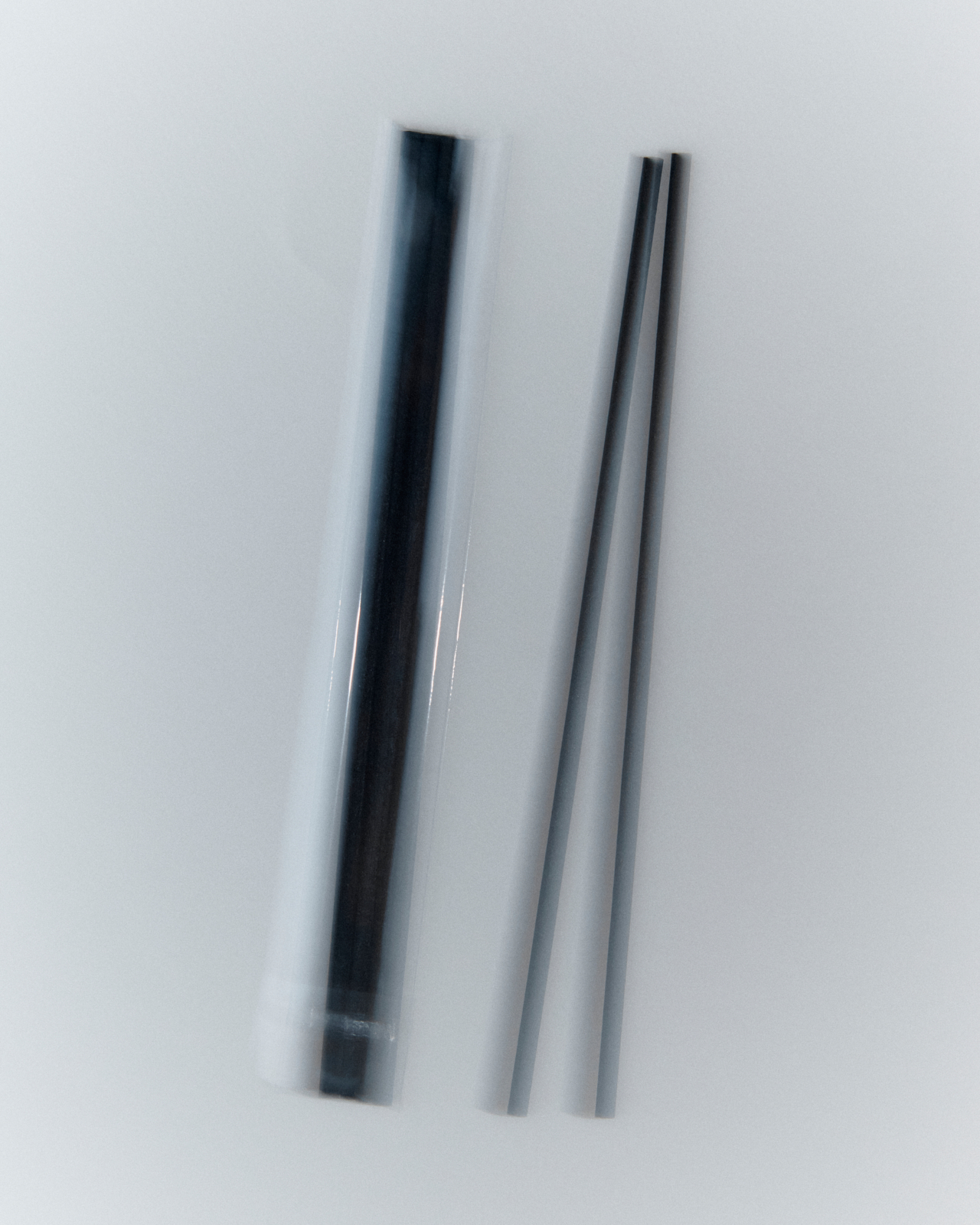 Fig Tree aroma oil glass bottle stacked on matte black diffuser vessel — layered product composition