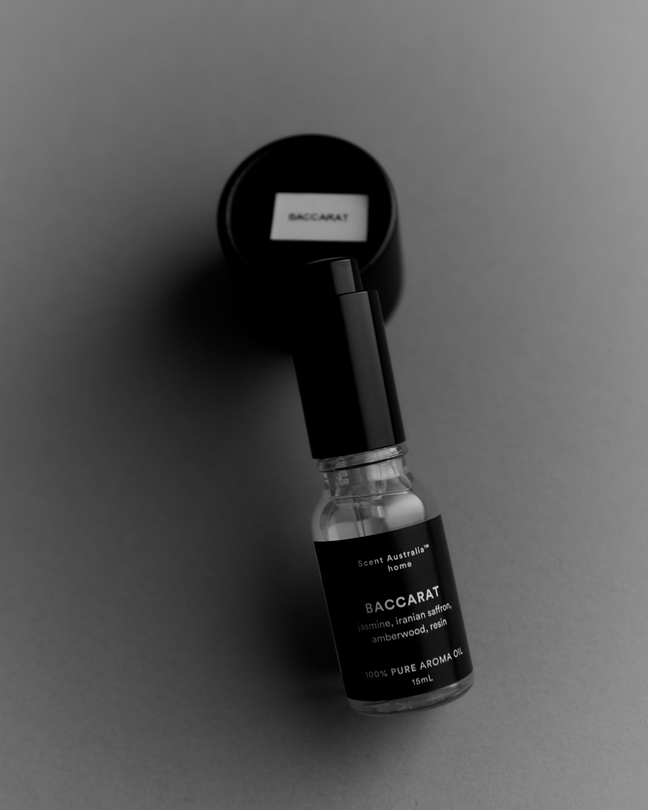 Baccarat 15ml aroma oil bottle on dark surface beside white chalk mark — moody product photography